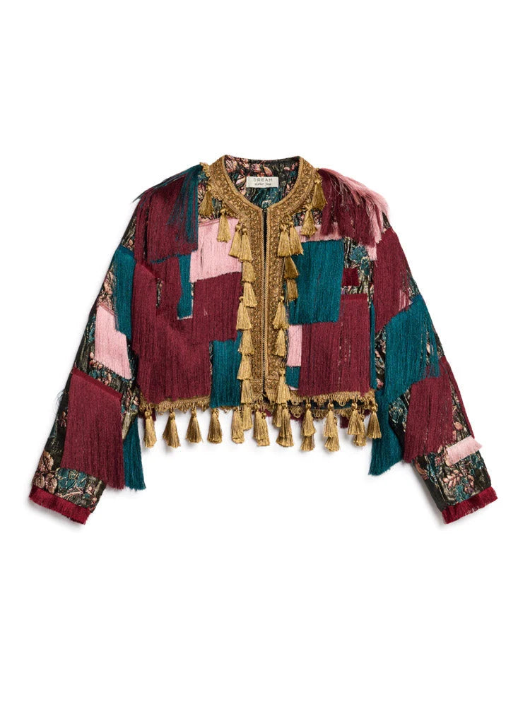 A bohemian-style cropped jacket featuring a patchwork design of burgundy, teal, and pink fabrics, adorned with gold fringe and tassels, shown against a plain white background.
